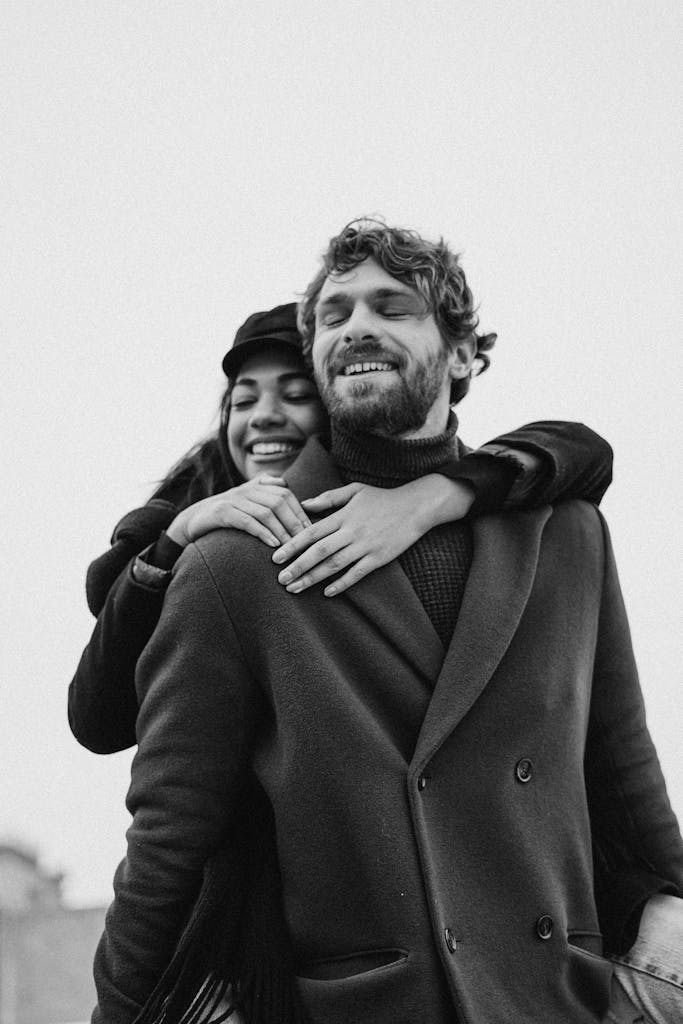 A joyful couple embracing in a black and white photograph, exuding warmth and affection.