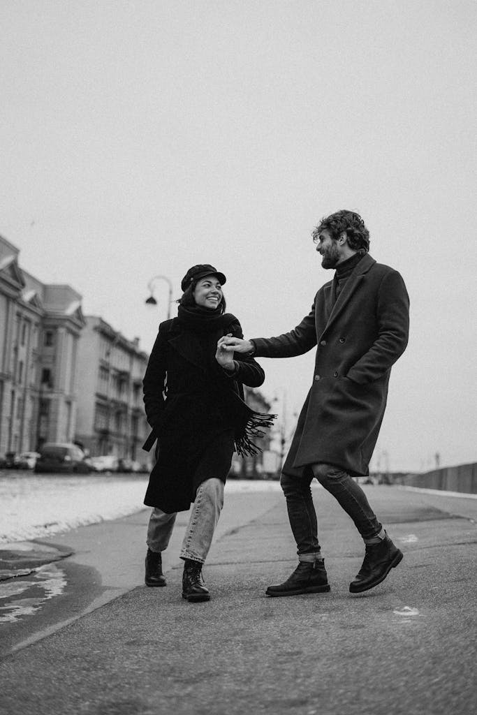 Couple holding hands and walking outdoors during winter in a city street.